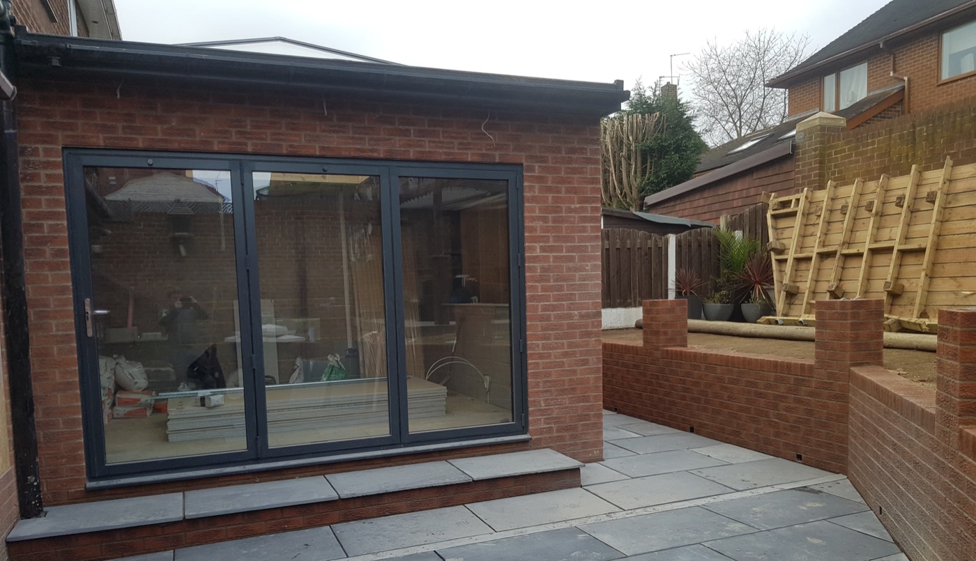 Brick extension with grey bi-fold doors and a new slab patio