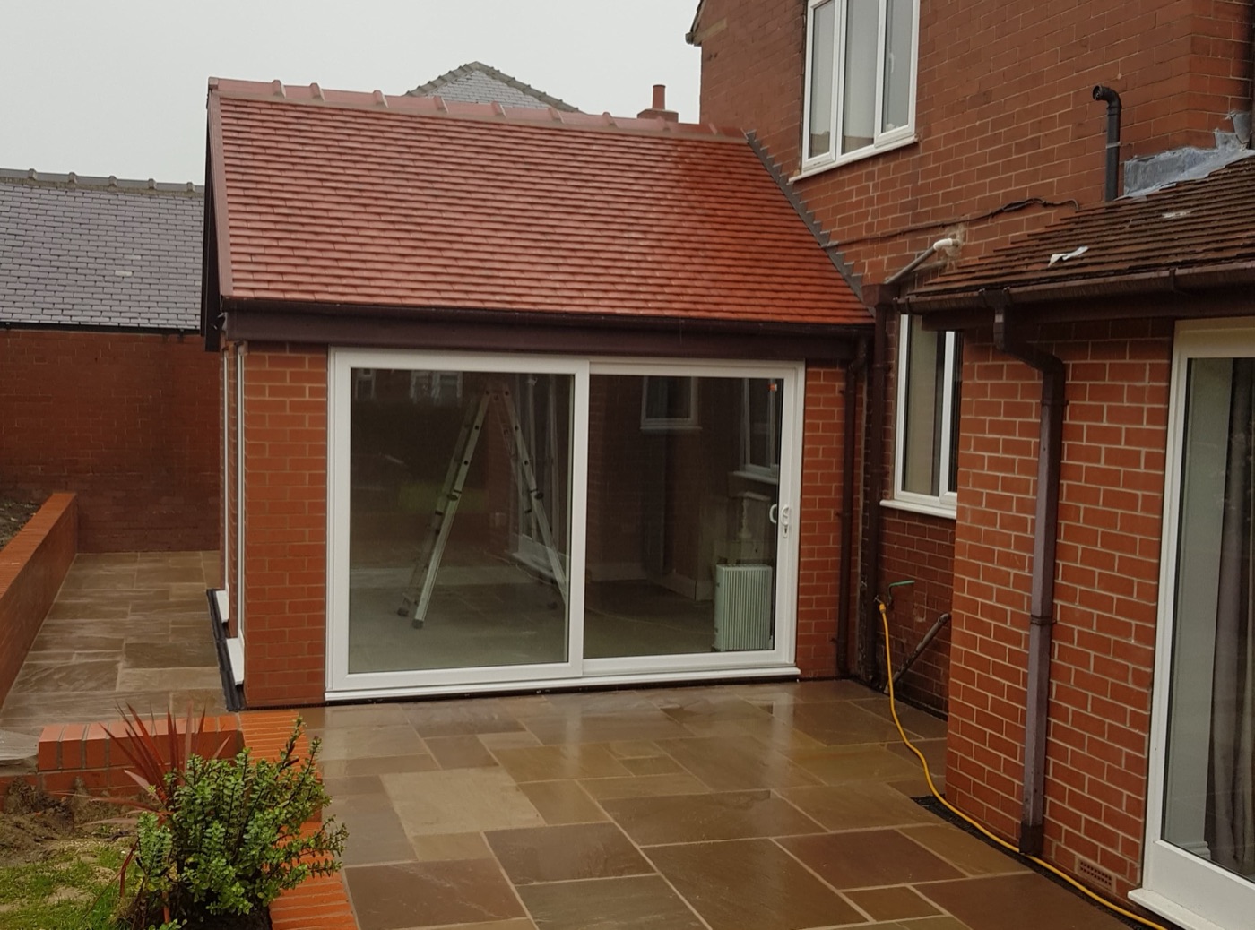 Brick extension with a clay-tiled roof, sliding doors and a new stone patio