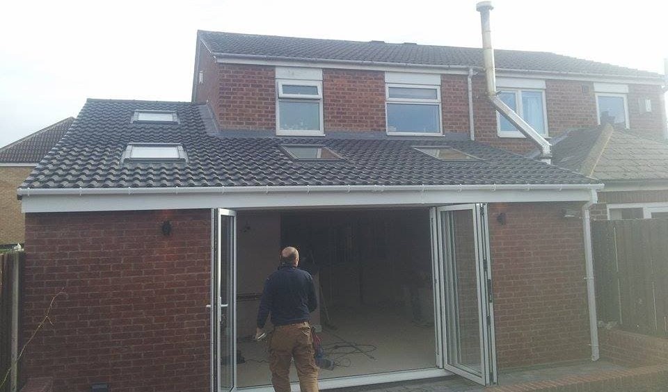 Tiled extension with roof windows and bi-fold doors open, with a builder at the door