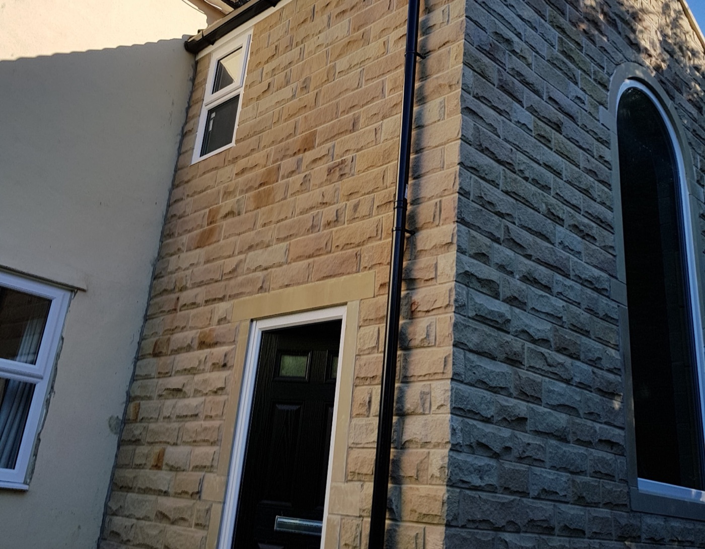 Two-storey stone extension with a tall arched window