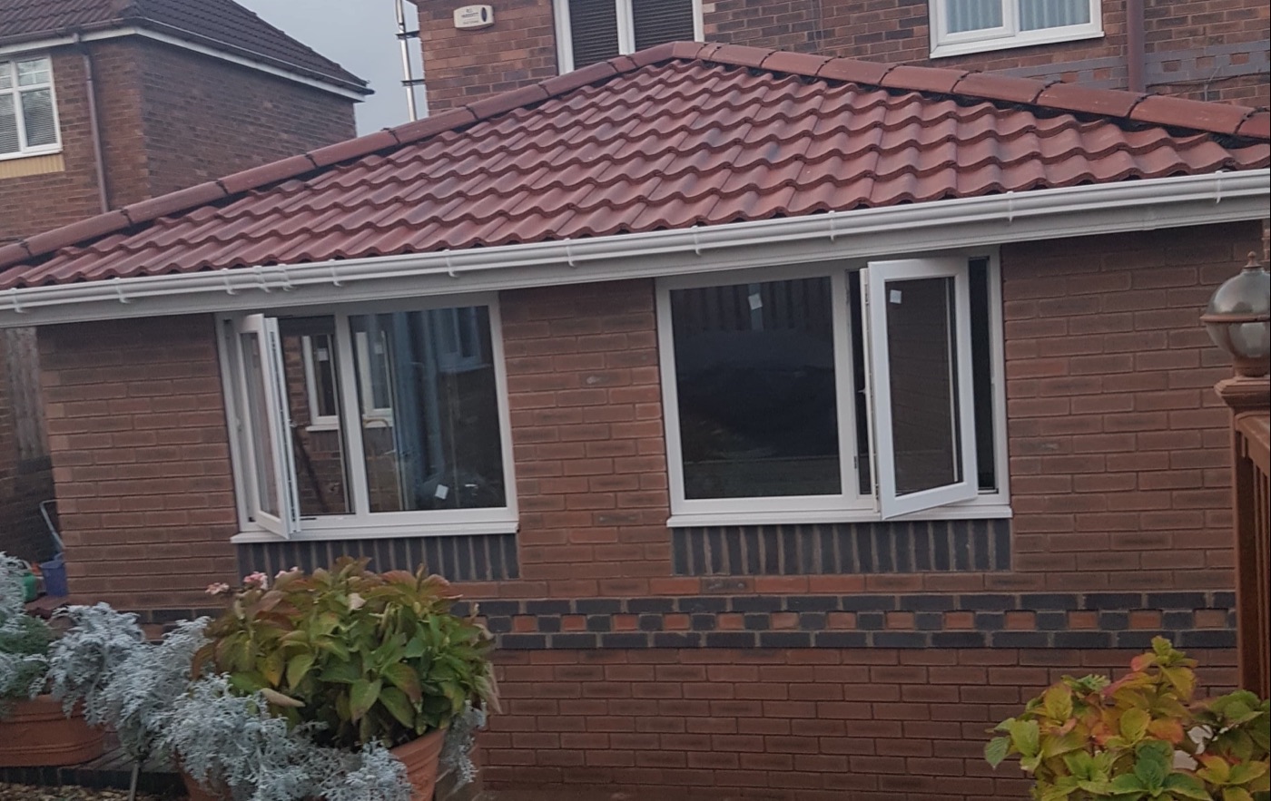 Brick extension with a new hipped tiled roof and white guttering